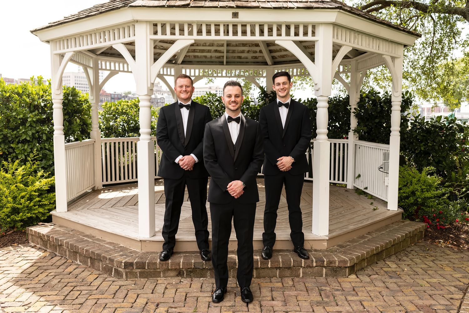 Elegant white gazebo decorated for a wedding ceremony with ornate details and landscaped surroundings.