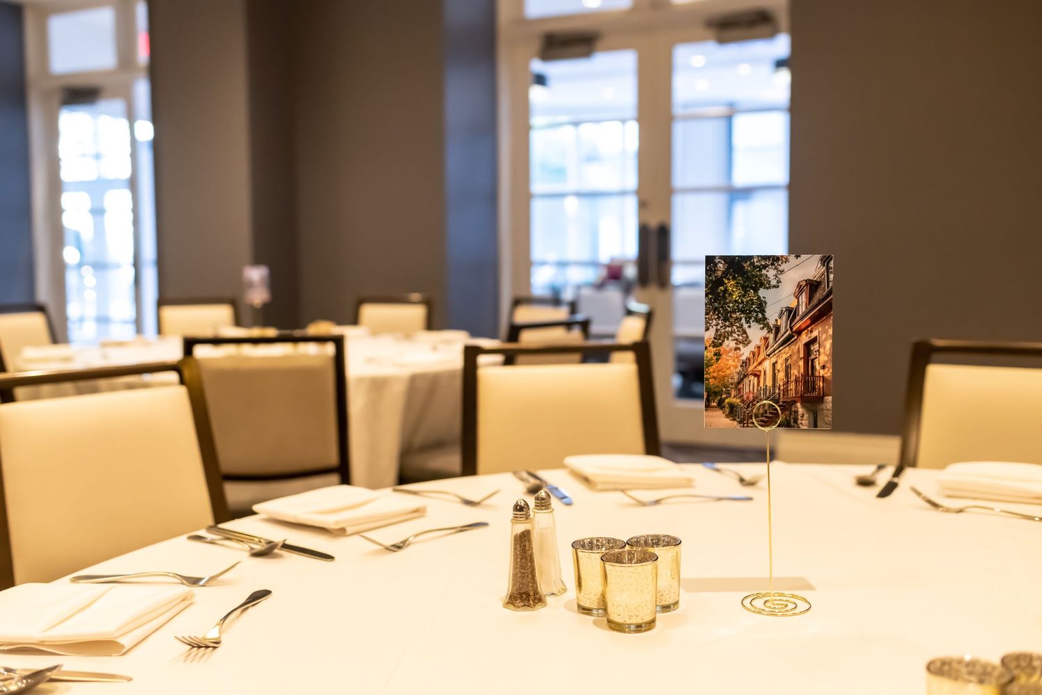 A formal dining table set with cream colored chairs and a small decorative sign in an elegant restaurant interior.