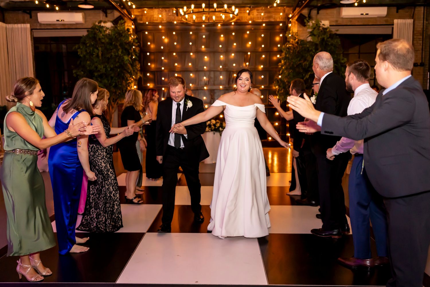 Guests form an aisle to celebrate as newlyweds make their grand exit at the reception.
