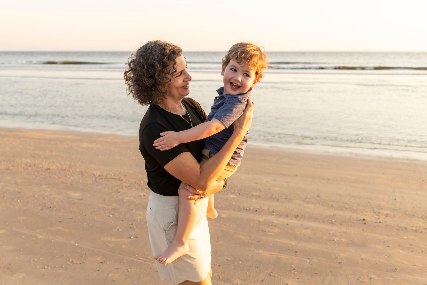 A joyful moment shared on the beach at sunset with golden light illuminating the sand.