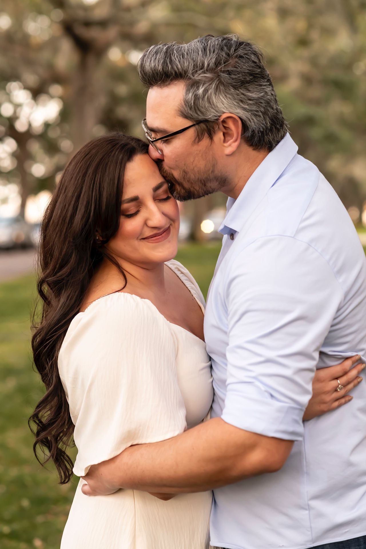 A romantic outdoor photoshoot showing a couple embracing in a park setting with multiple tender moments captured.