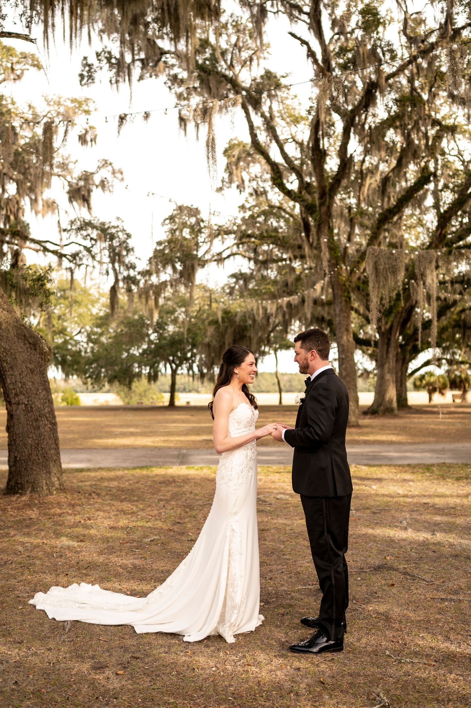 Couple shares intimate moment under spanish moss draped trees during golden hour wedding photoshoot.