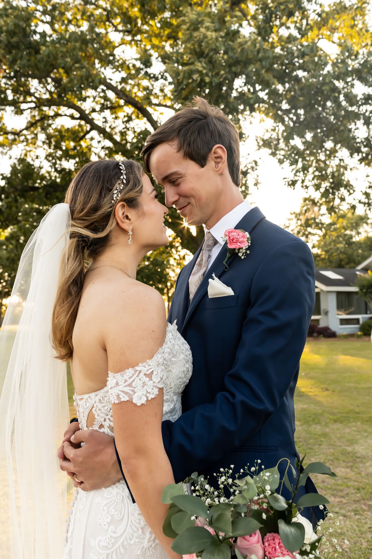 A romantic wedding moment between a couple sharing an intimate embrace outdoors during golden hour lighting.