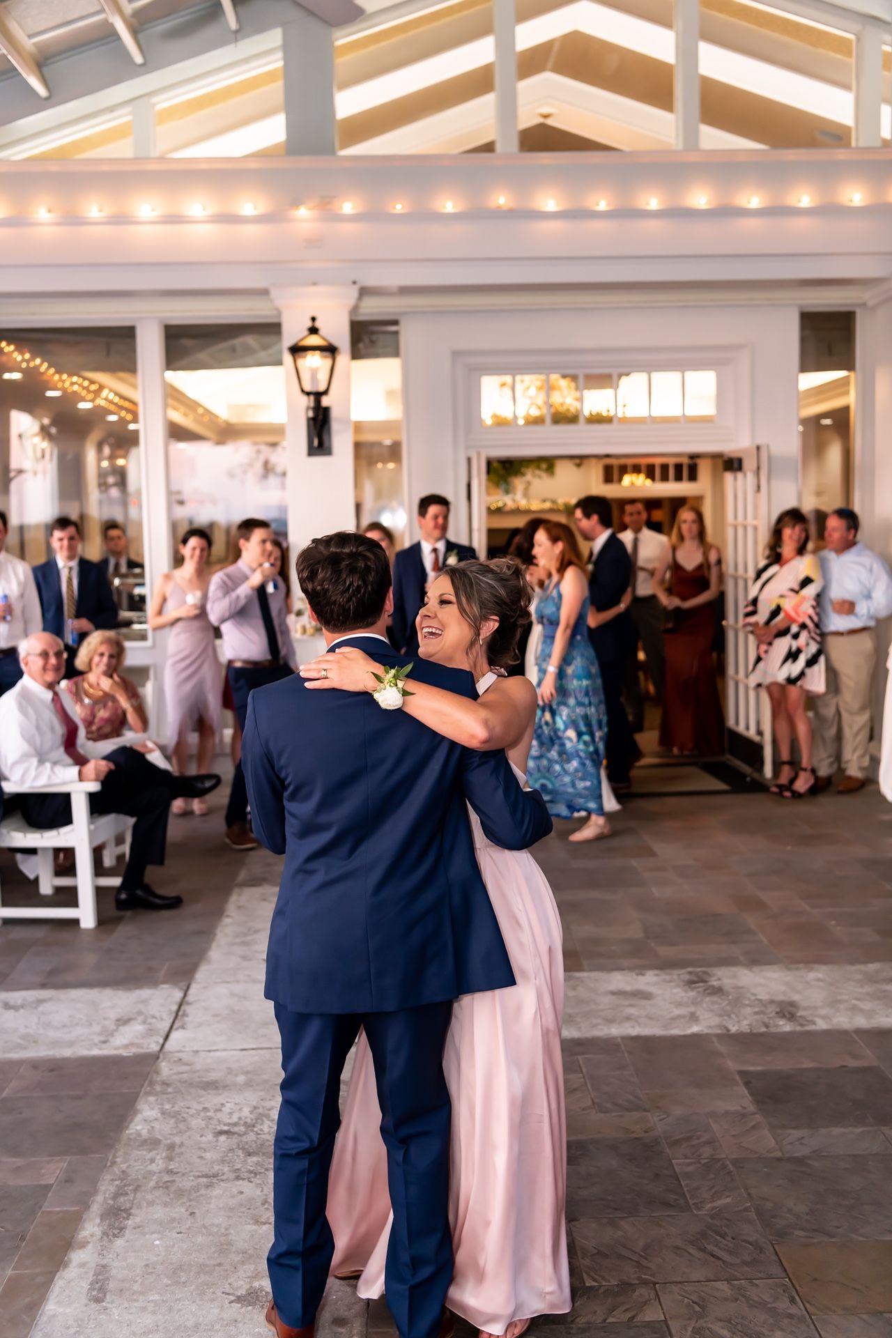 Wedding celebration sequence showing couples dancing together at an elegant venue with string lights overhead.