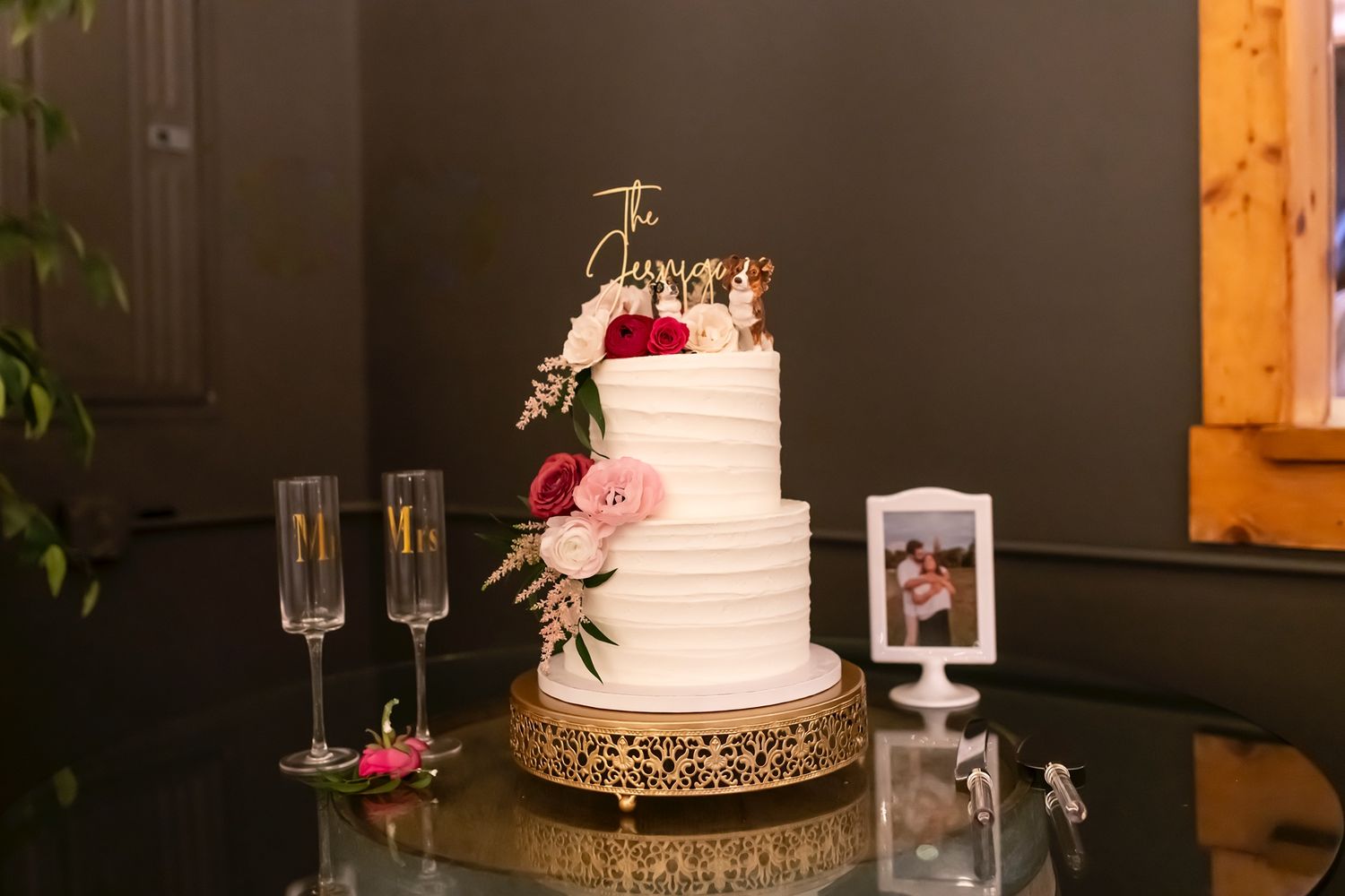 A collection of sophisticated wedding cakes and cocktails elegantly displayed at an indoor reception venue with dark walls.