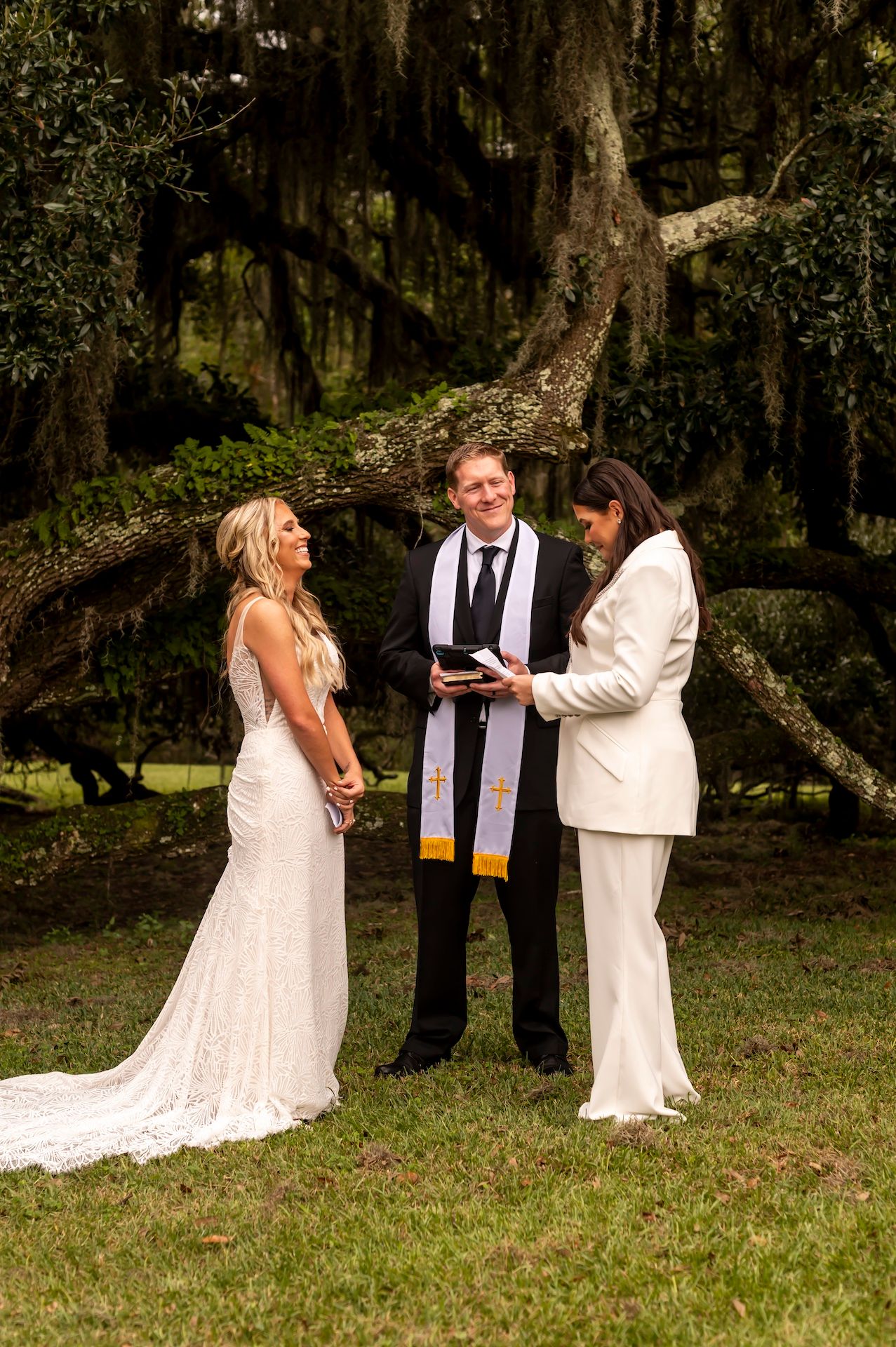 A romantic outdoor wedding ceremony unfolds under mossy oak trees in elegant rustic style.