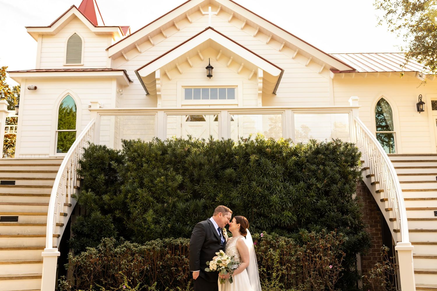 Bride and groom with elegant white chapel on Tybee Island.