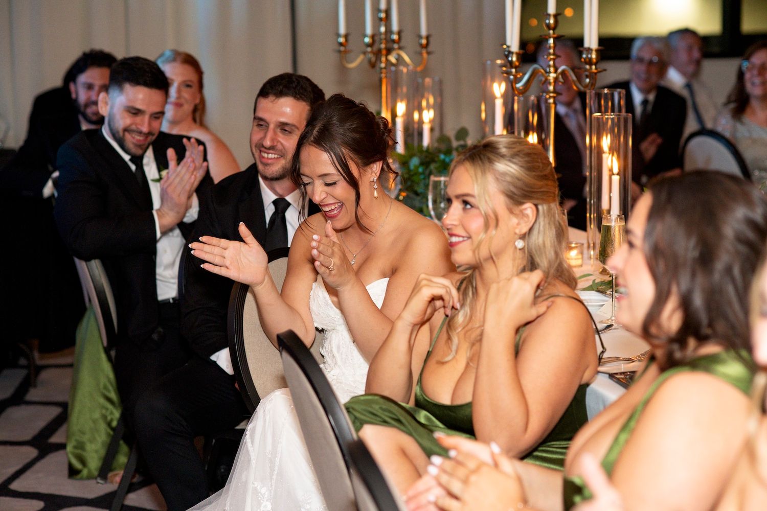Wedding reception guests dancing and celebrating together on a dance floor with candlelit tables in the background.