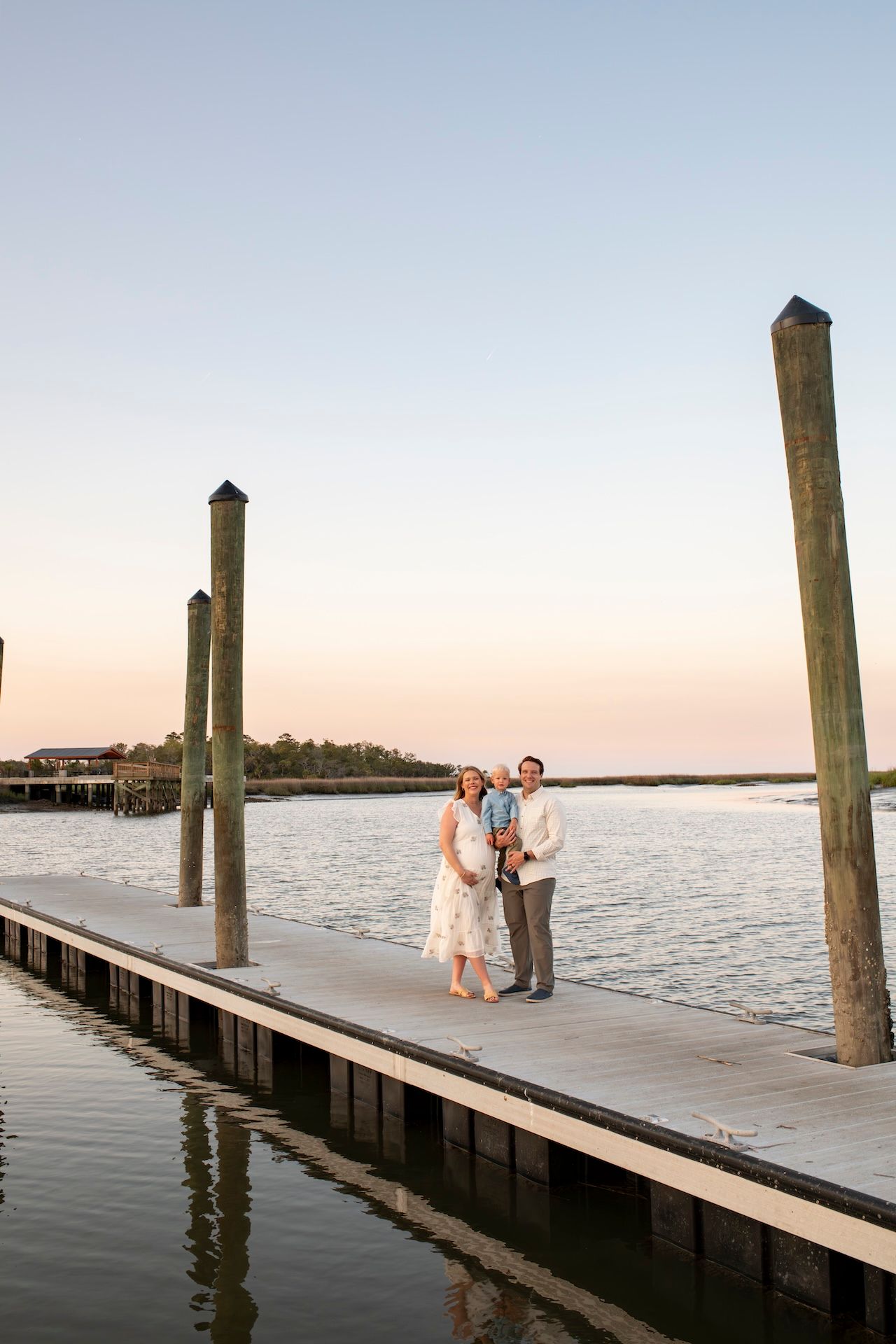 A family of three taking family portrait on dock in Savannah, Georgia.