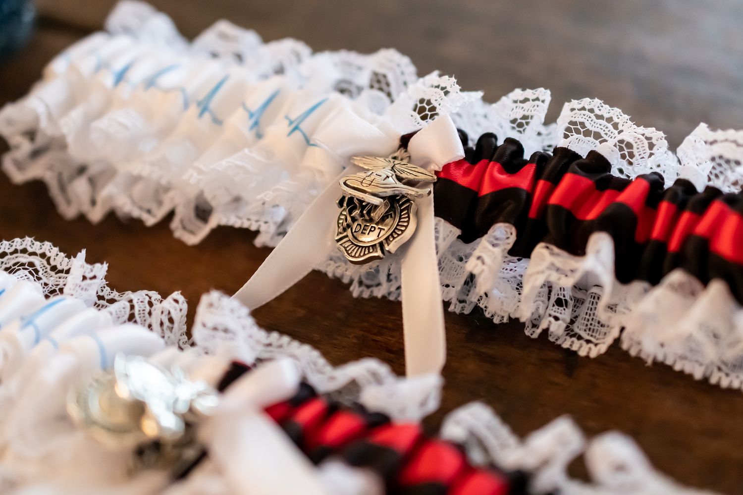A white lace and red satin wedding garter set with a decorative bow detail rests on a wooden surface.