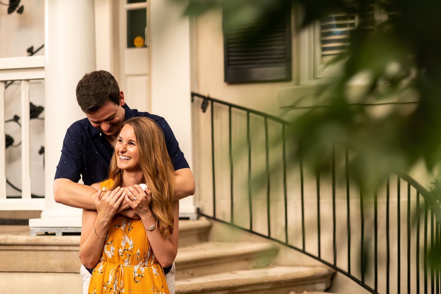 A romantic couple shares an intimate moment on their front porch steps during golden hour.