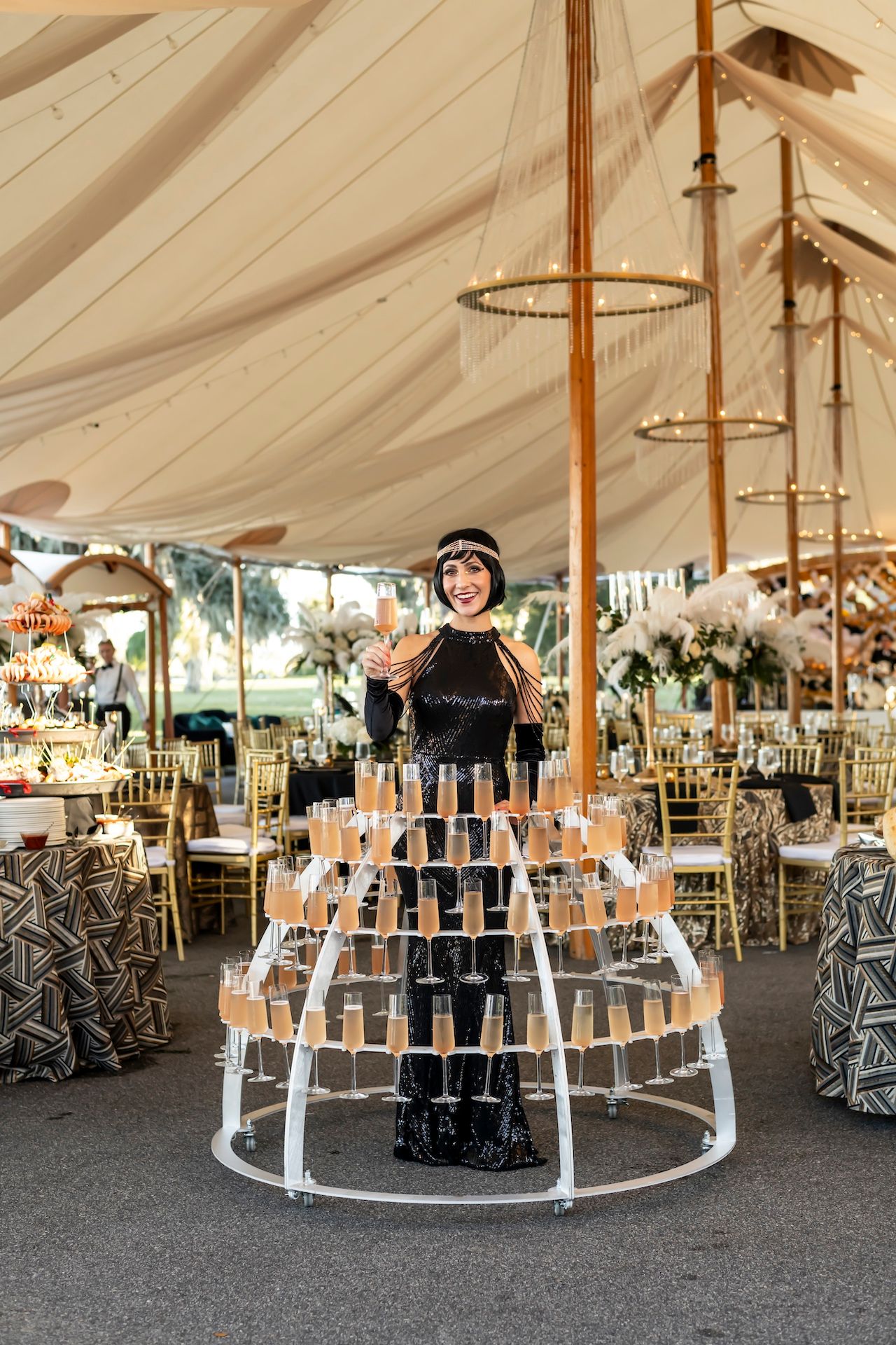Wedding reception tent setup with symmetrical displays of photo frames arranged in curved tiers under white canopy lighting.