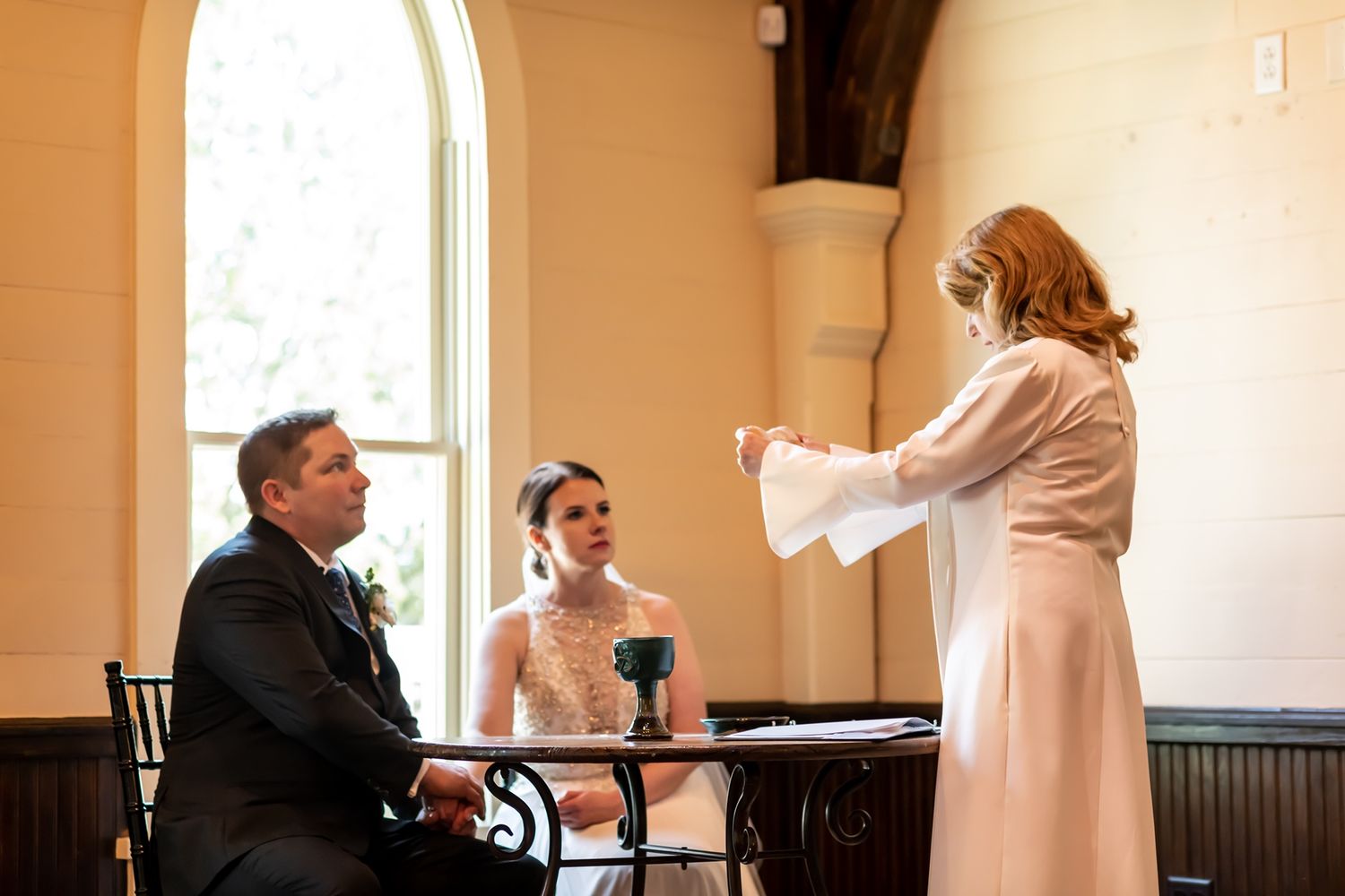 People seated at ceremony during signing arrangements at floral-decorated chapel venue.