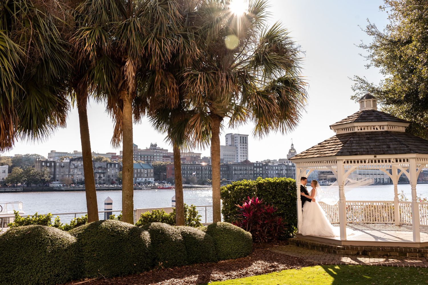 Waterfront gazebo and palm trees overlooking harbor at sunset in Savannah, Georgia.