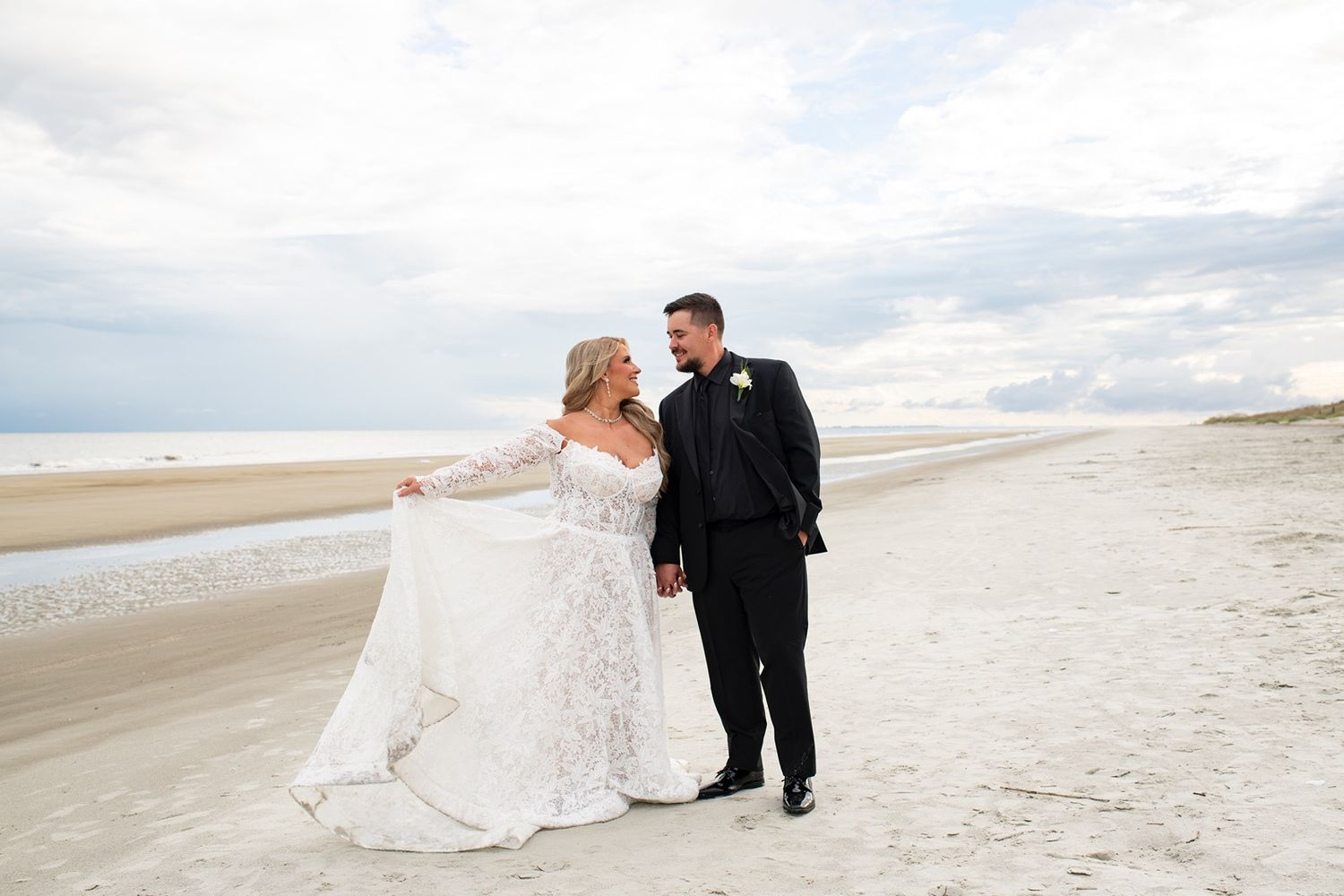 A couple shares a romantic moment on a cloudy beach as waves roll in along the shoreline.