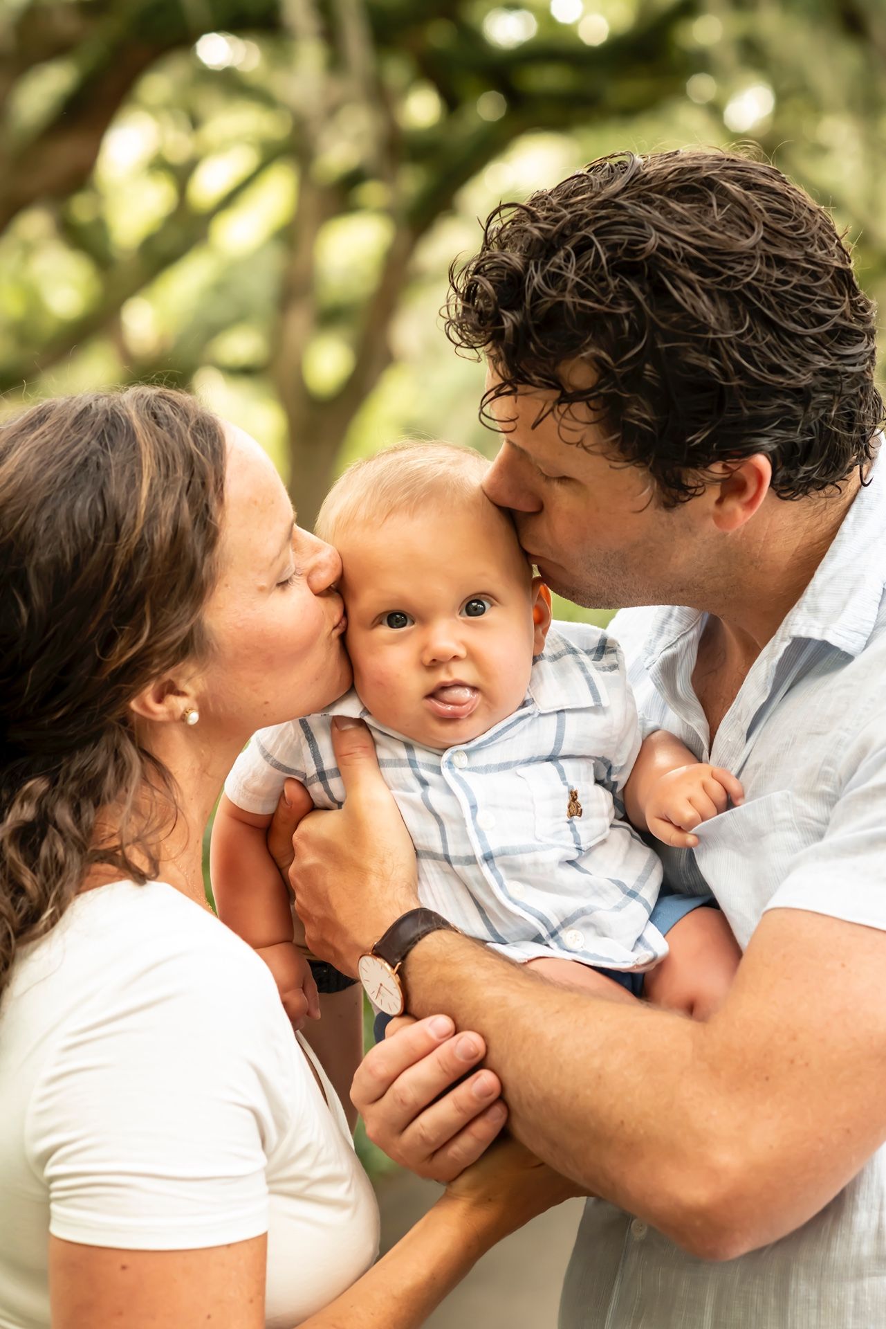 Sweet family portrait sequence showing playful kissing and snuggling outdoors with natural bokeh lighting.