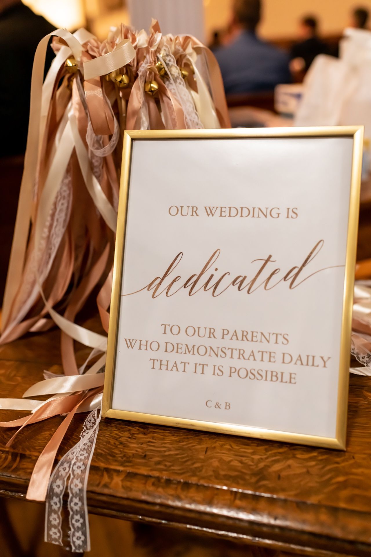 Wedding stationery details showing elegant calligraphy text and ribbons on a rustic wooden table.