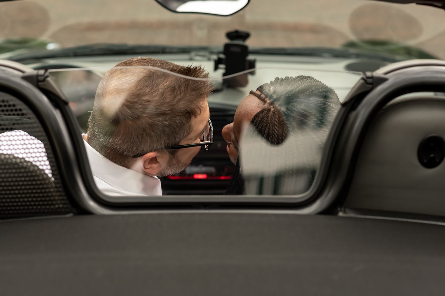 Side view of people chatting inside a parked vehicle through car window.