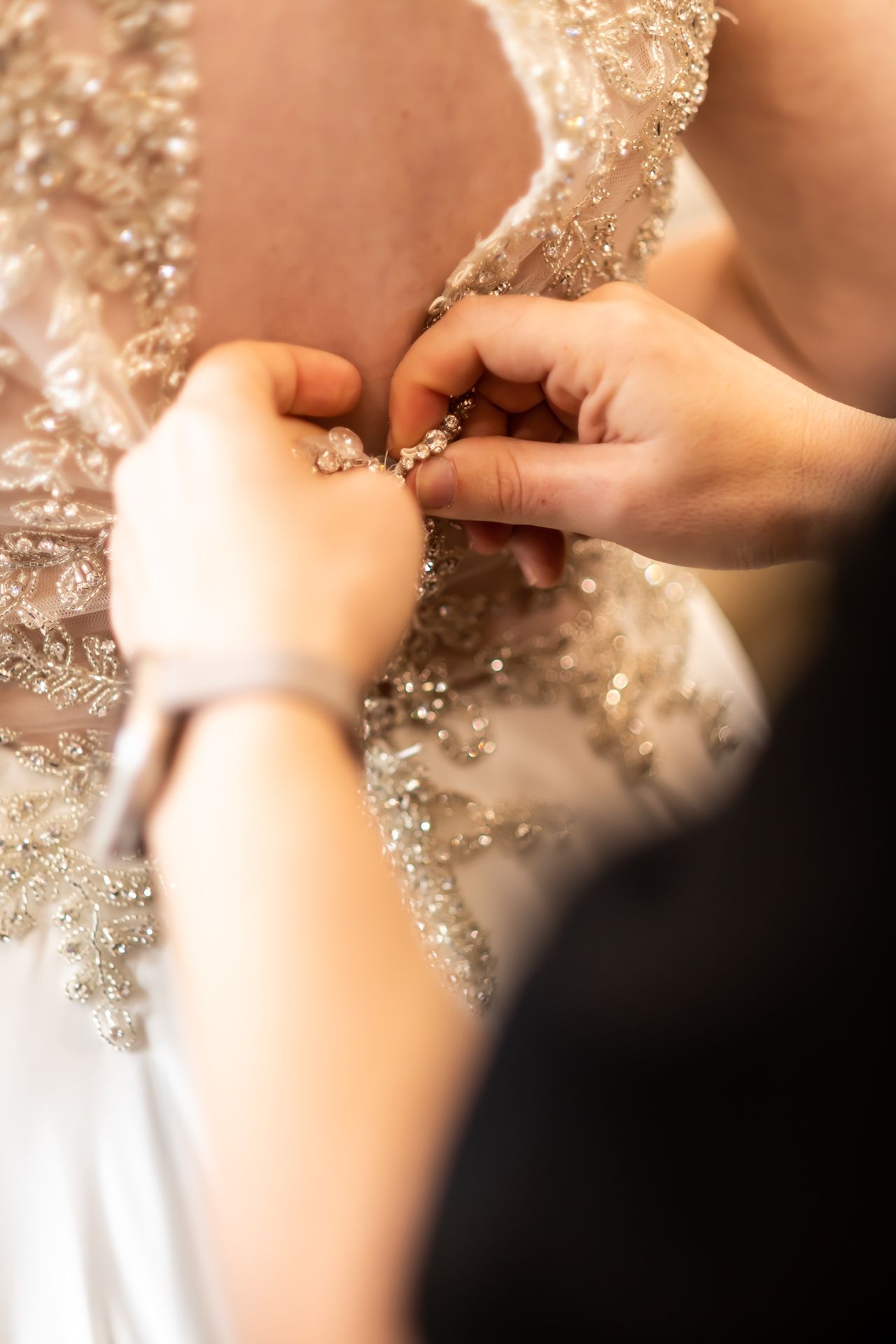 Close-up of hands adjusting delicate lace details on a wedding dress.