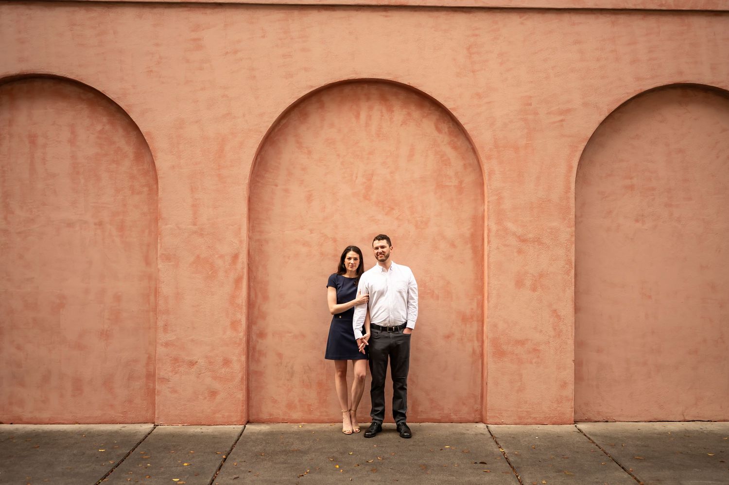 A sequence of romantic couple poses against a terracotta wall during an intimate photography session.
