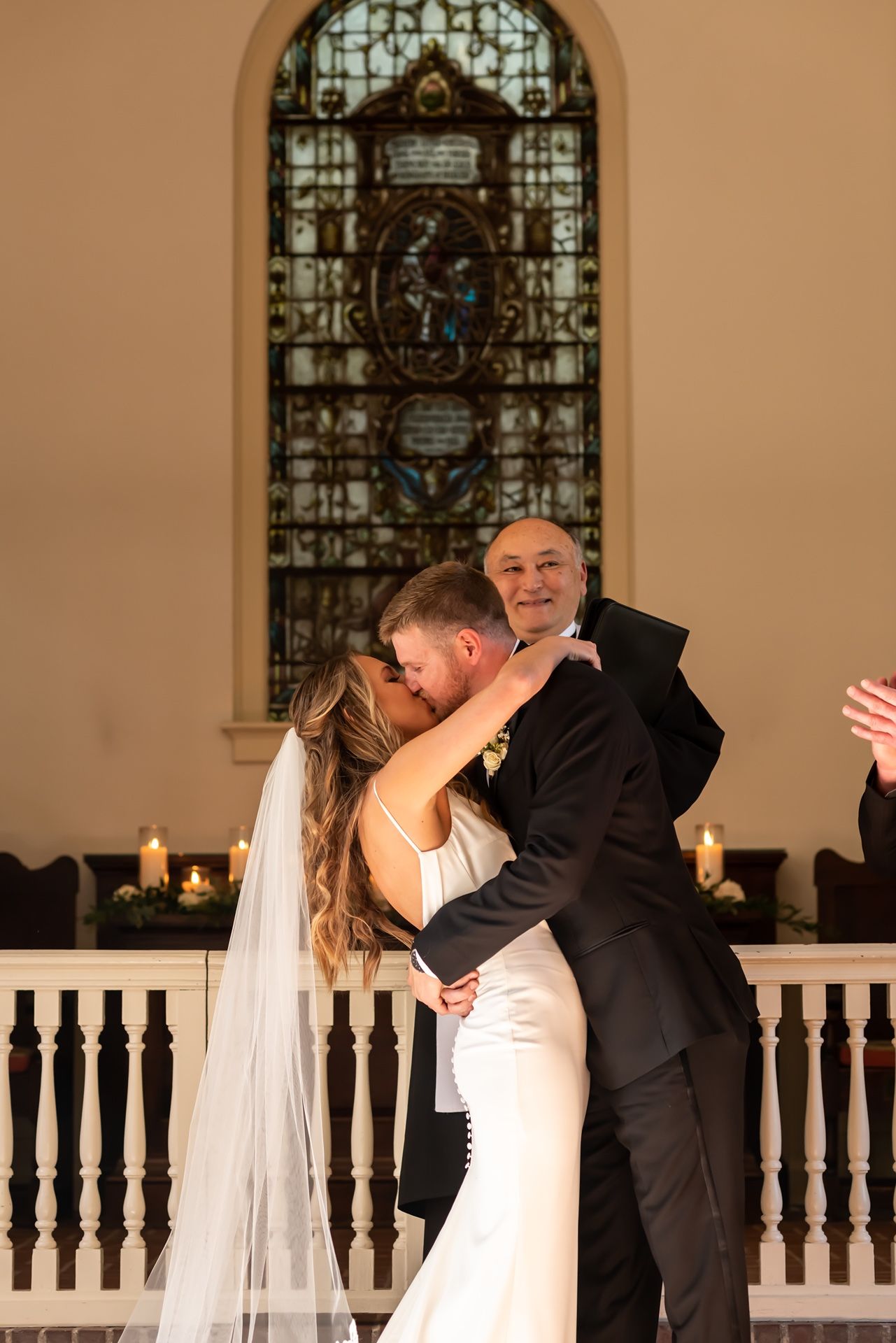 Beautiful wedding ceremony sequence showing joyful couple sharing their first kiss by ornate stained glass windows in church.