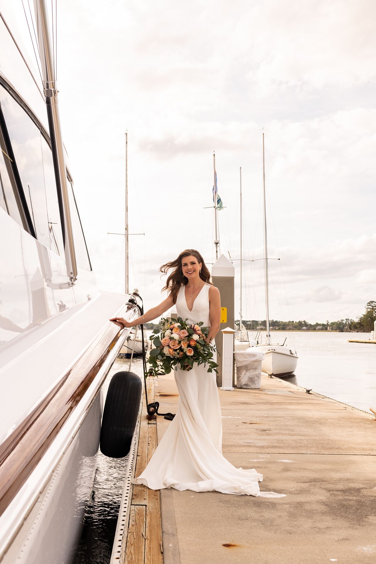 Nautical bridal photography session featuring white gown against yacht club backdrop.