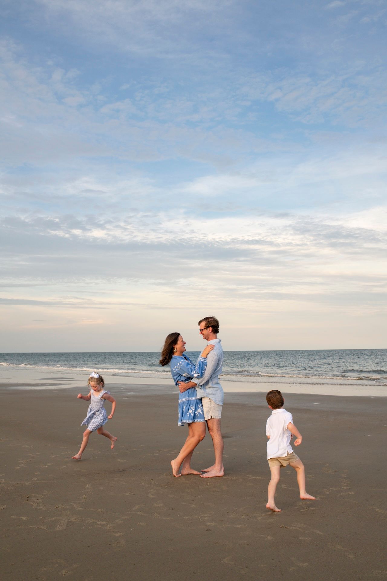 Children running around parents during a family portrait session on the beach on Hilton Head.