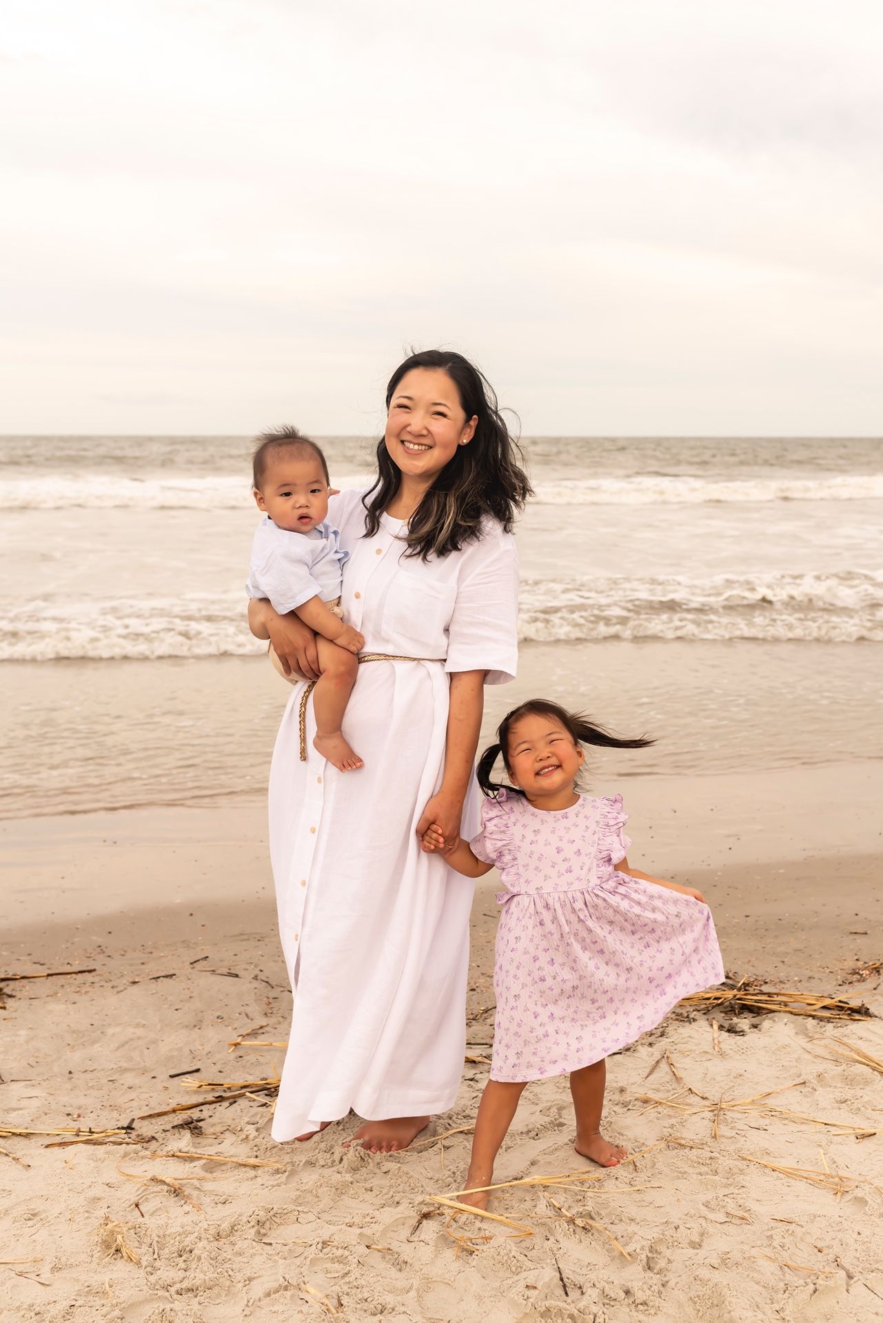 A joyful family moment captured on the beach with waves and sand during sunset.