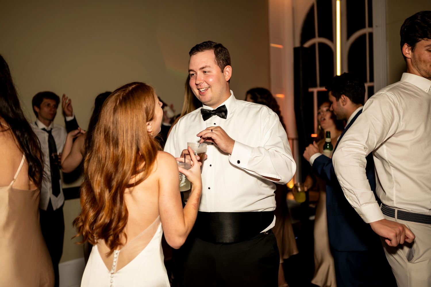 Dancing couple at wedding reception during evening celebration on bright dance floor.