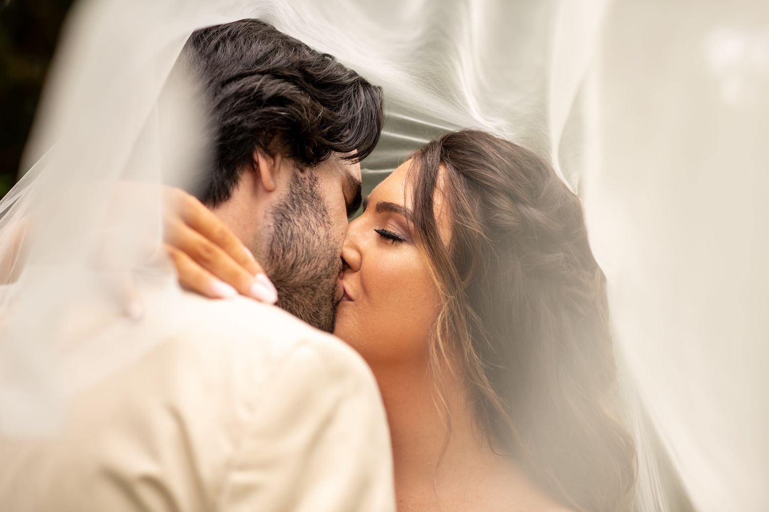 Romantic close-up wedding photo of couple sharing an intimate moment under a sheer veil.