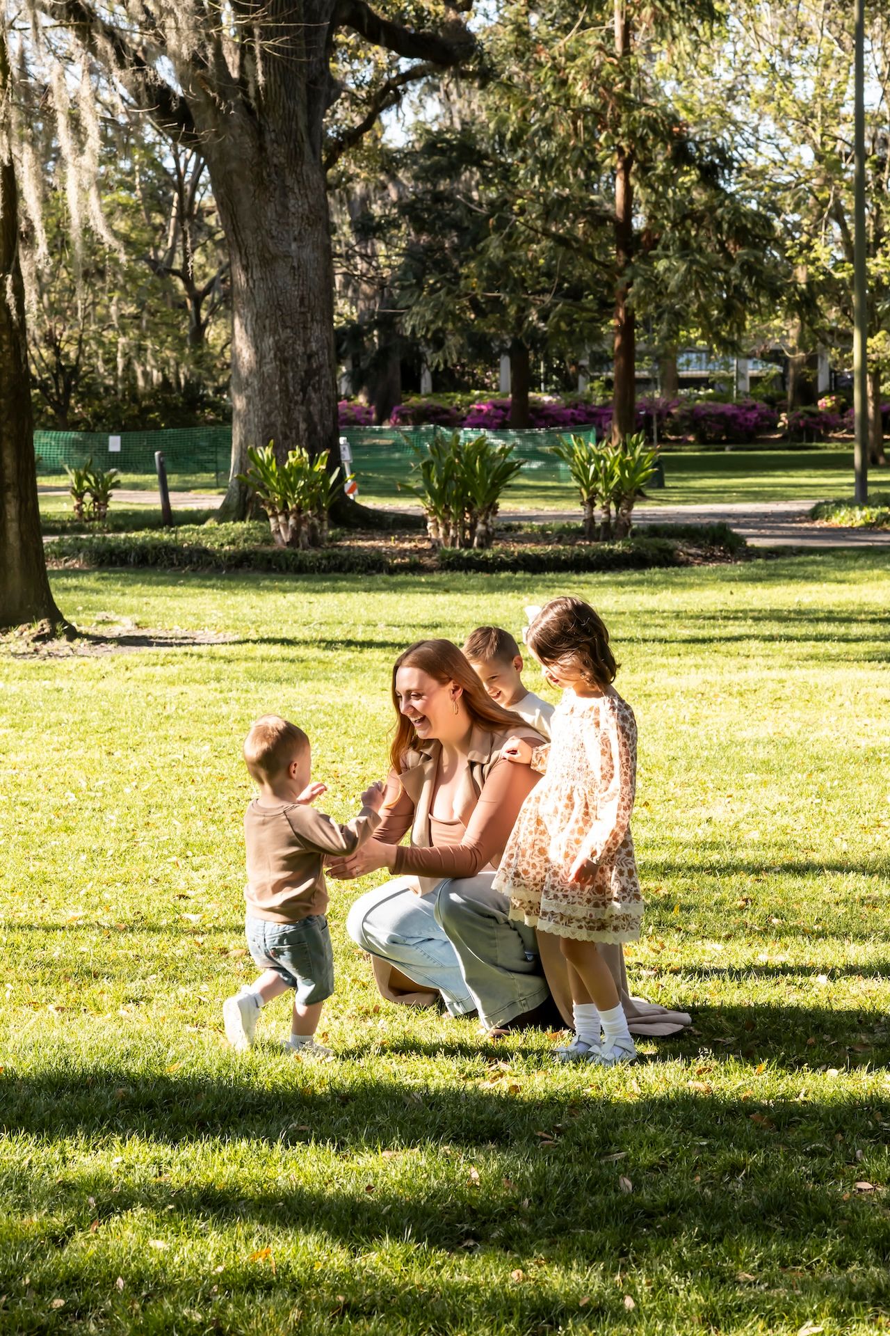 People enjoying a sunny day in a park with Spanish moss draped trees and lush green grass.