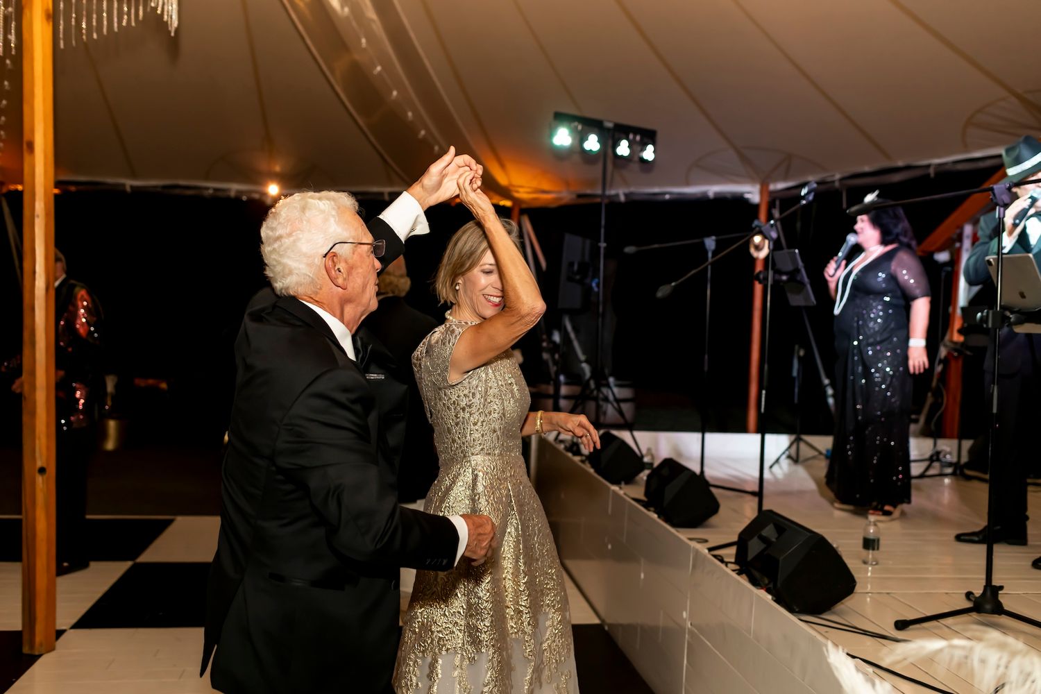 A couple shares an intimate dance in a dimly lit reception tent during their wedding celebration.