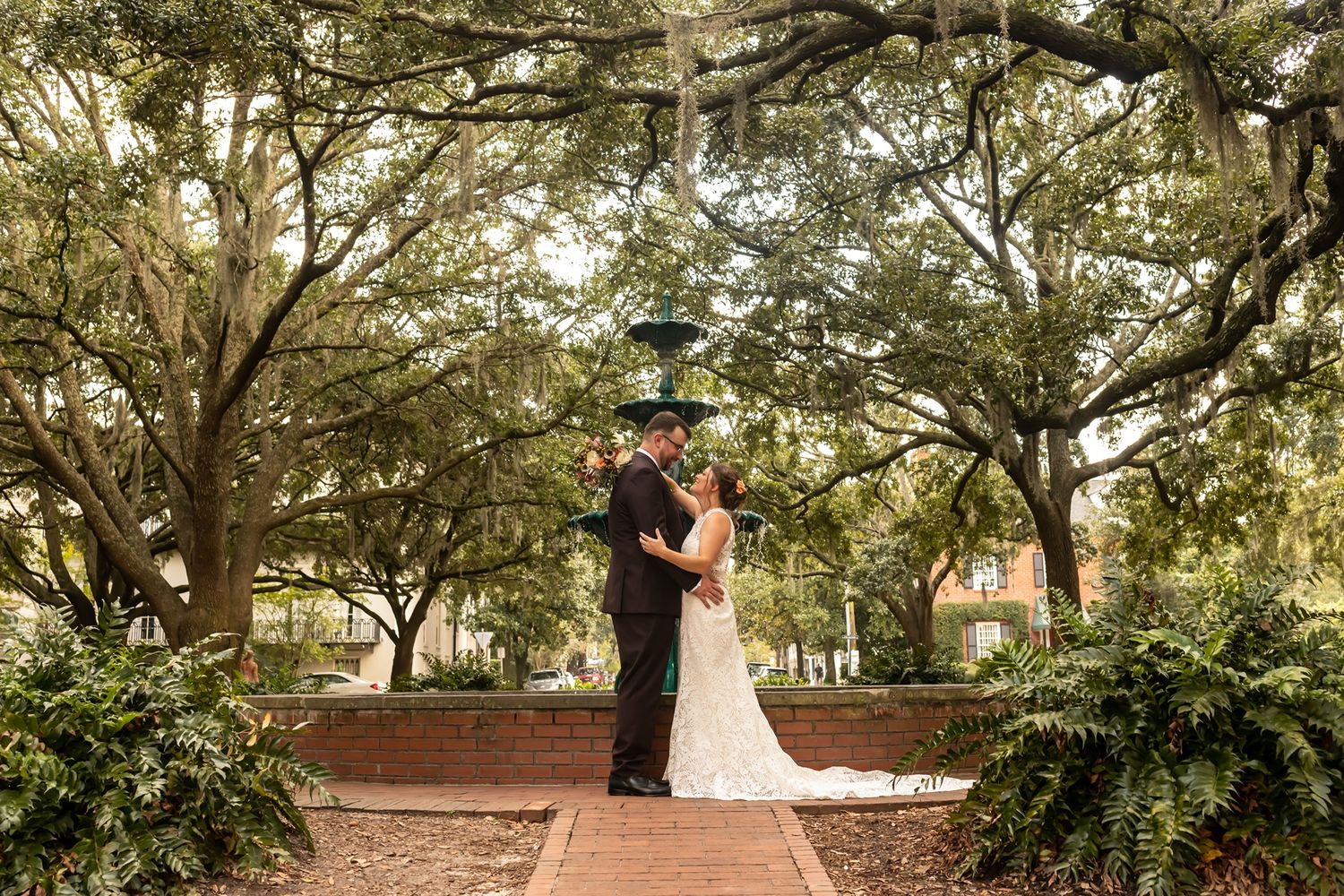 A romantic outdoor photo series showing a couple in formal attire embracing under moss-draped oak trees.