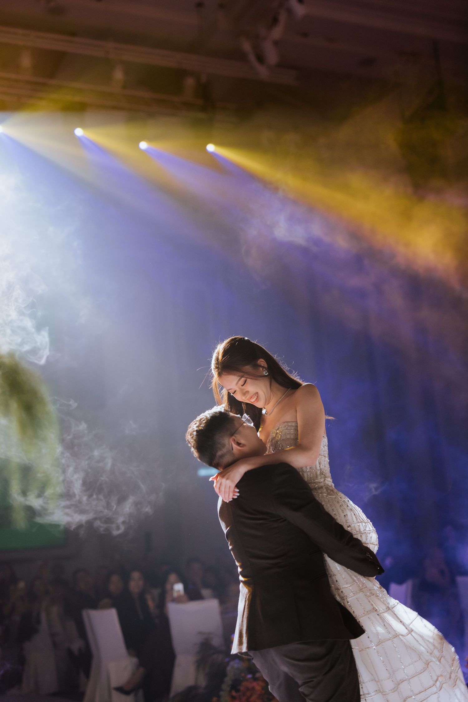 A couple shares a romantic first dance moment on their wedding day as fog and dramatic lighting create an ethereal atmosphere.