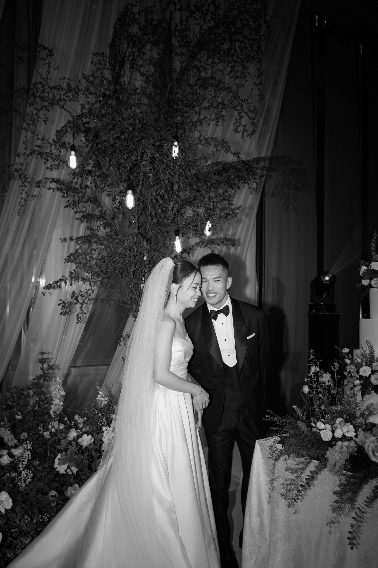 Black and white wedding dance photo series showing couple gracefully spinning in formal attire amidst floral decorations.