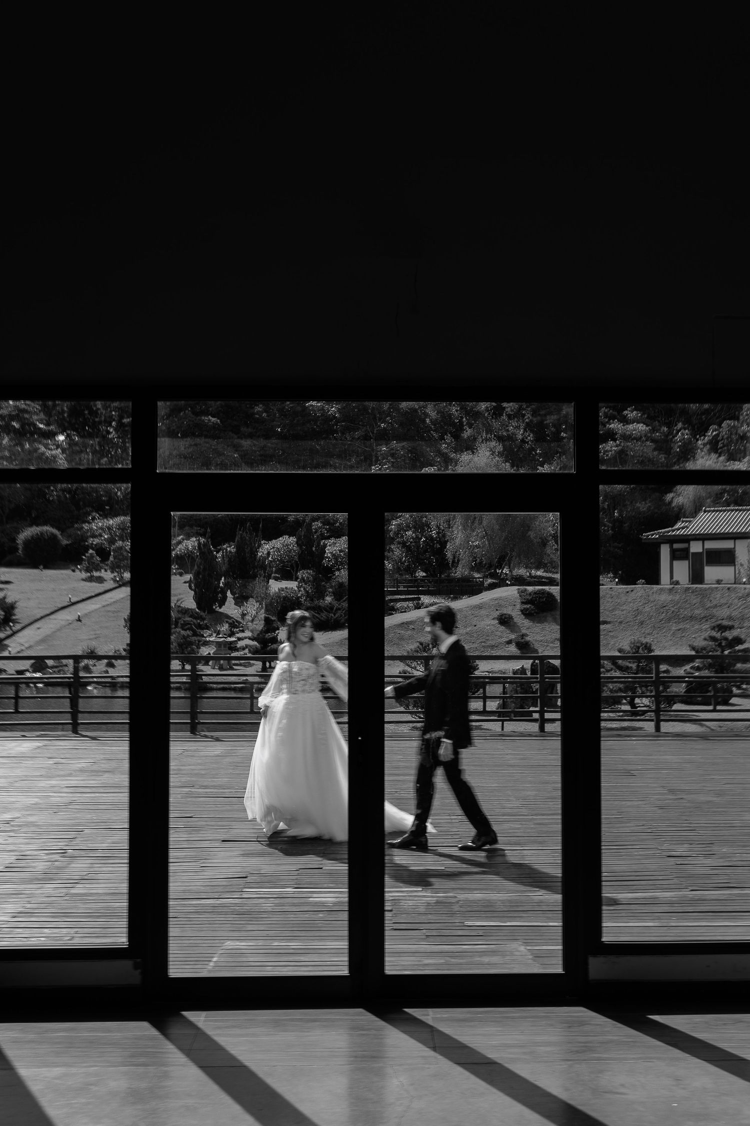 Artistic silhouette of wedding party through window panes creating geometric shadows.