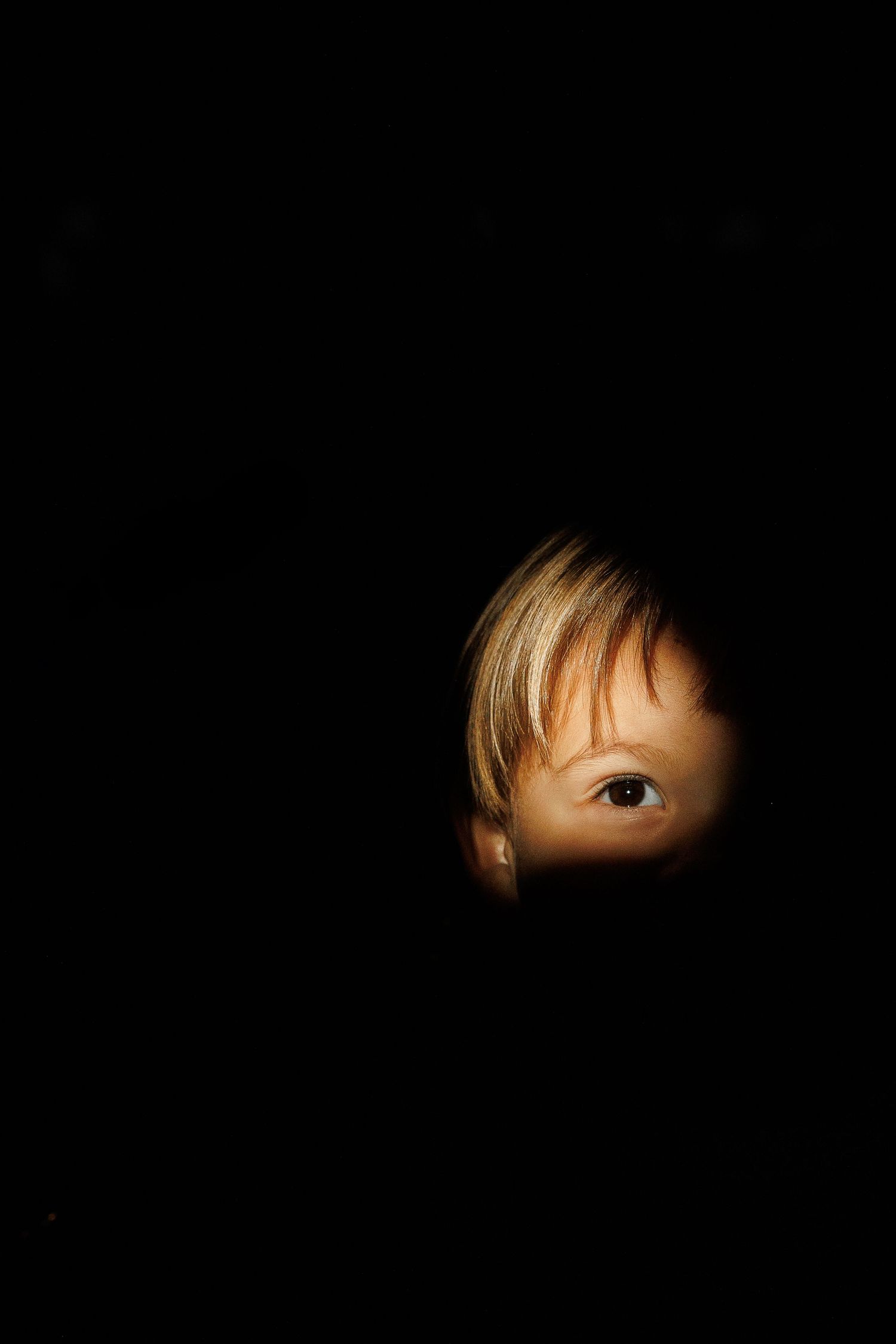 Dramatic portrait with eyes emerging from darkness in cinematic lighting.