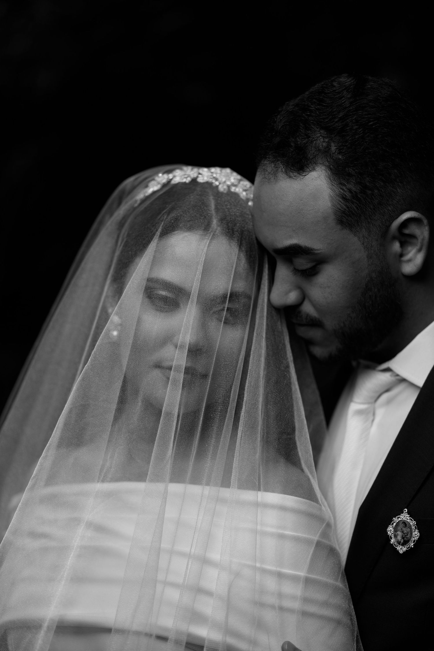 Romantic black and white portrait through delicate wedding veil with soft lighting.