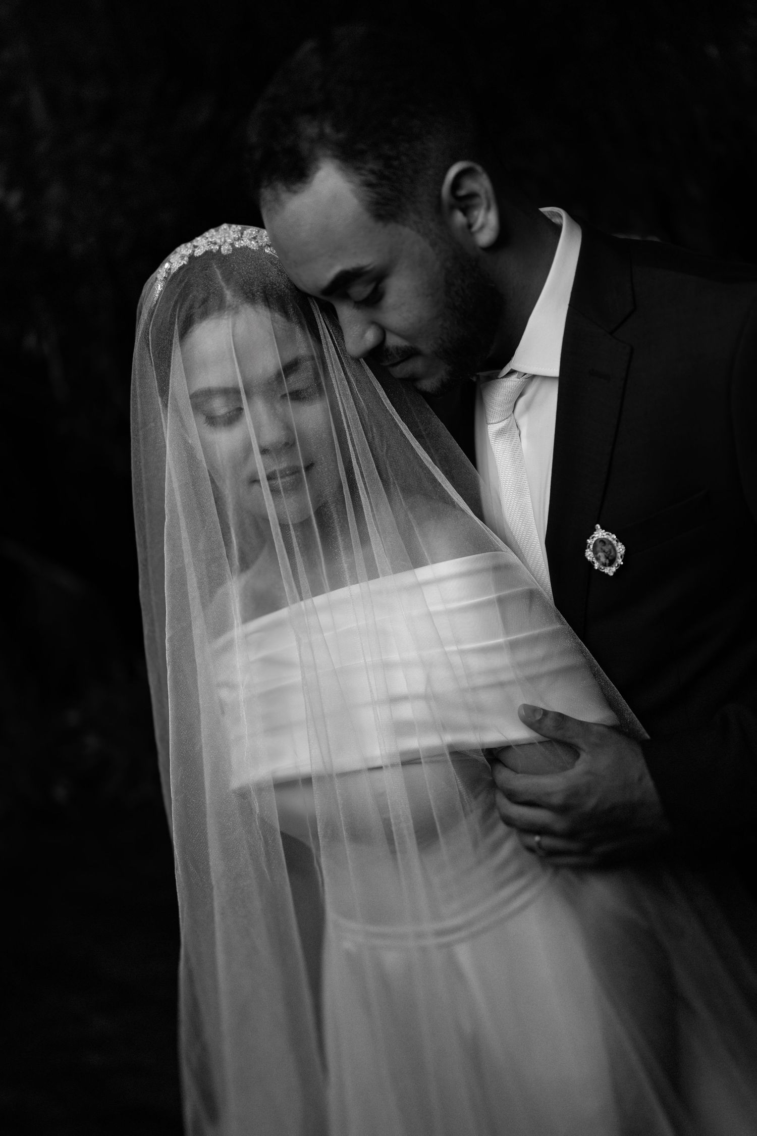 Artistic black and white wedding photography with flowing veil and dramatic shadows.