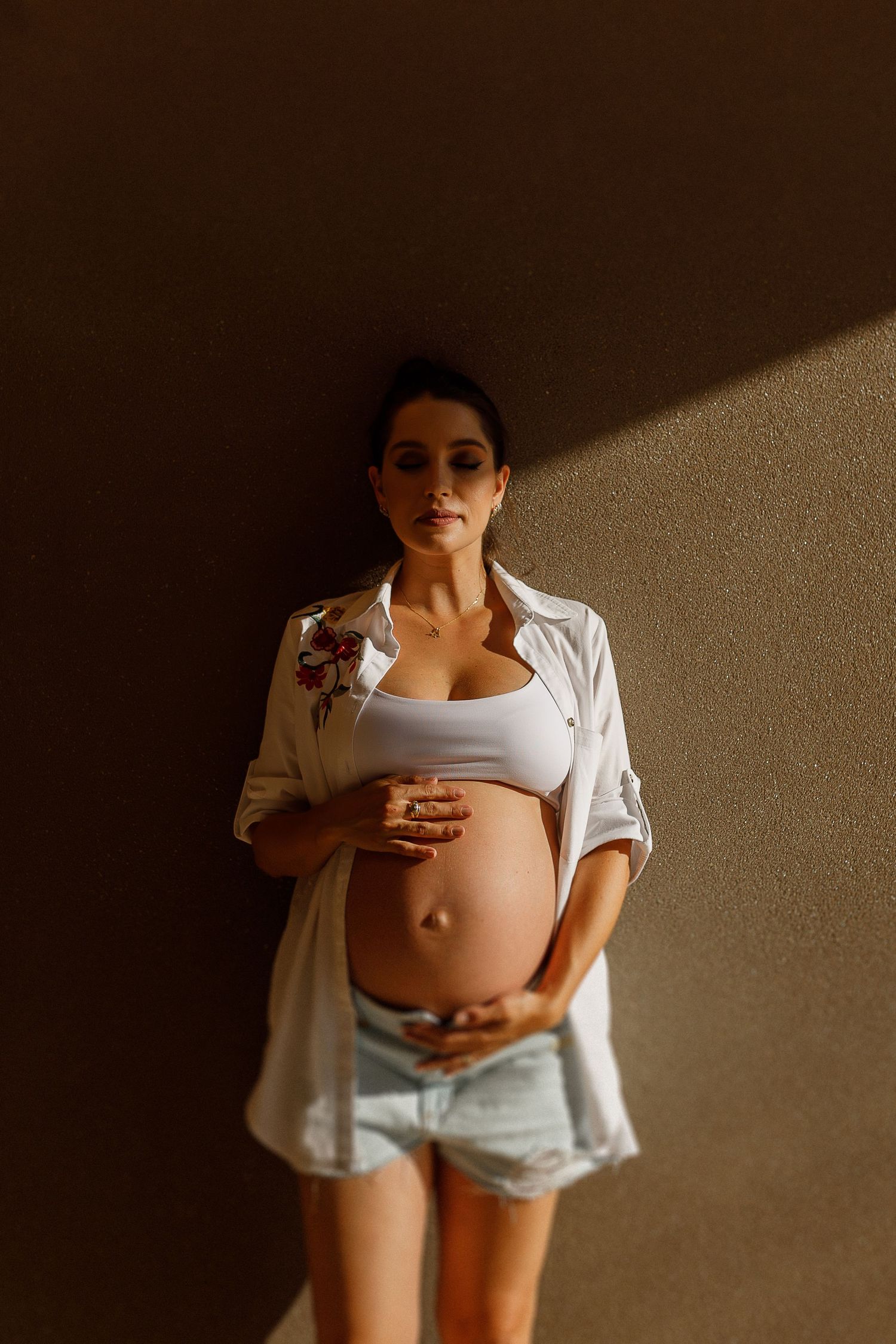 Artistic maternity photos with dramatic lighting showing pregnancy silhouette against dark background.