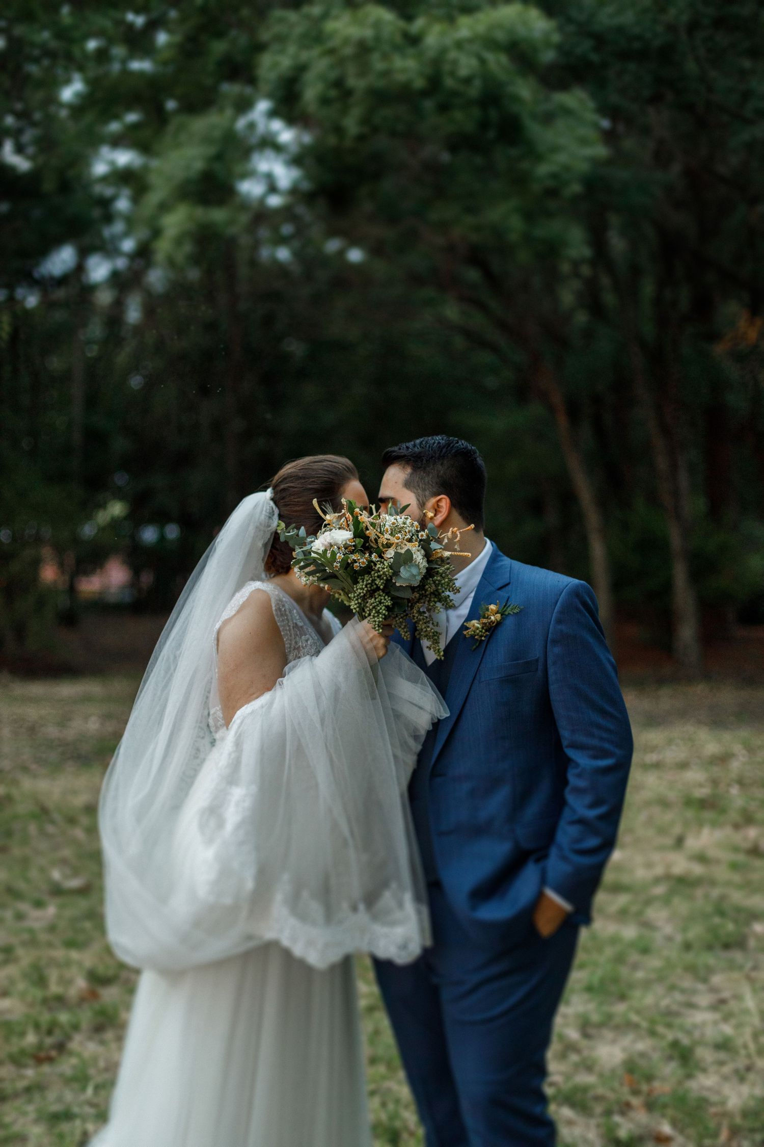 Wedding couple sharing an intimate moment in a wooded outdoor setting.