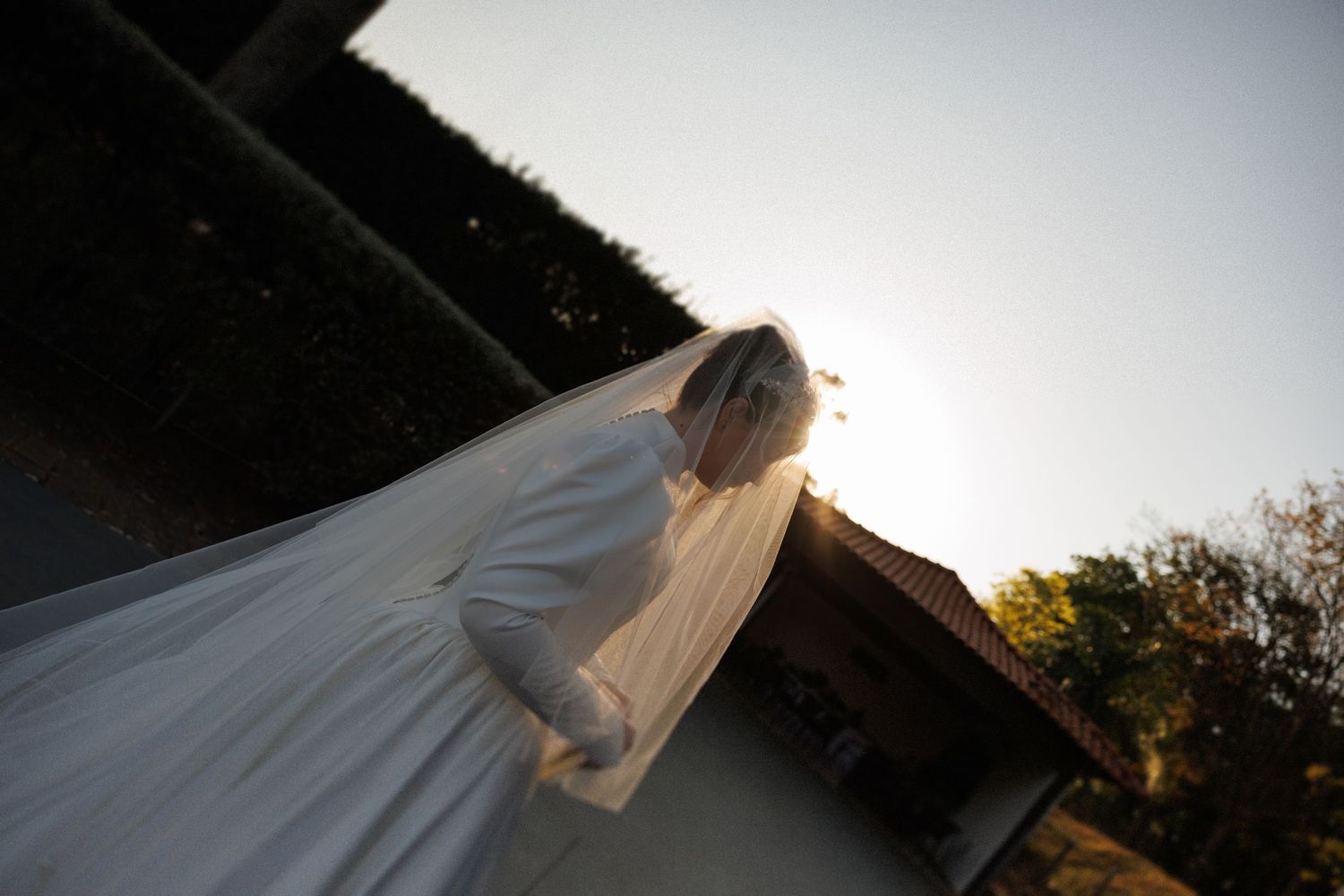 A bride walks gracefully through a garden setting during sunset.