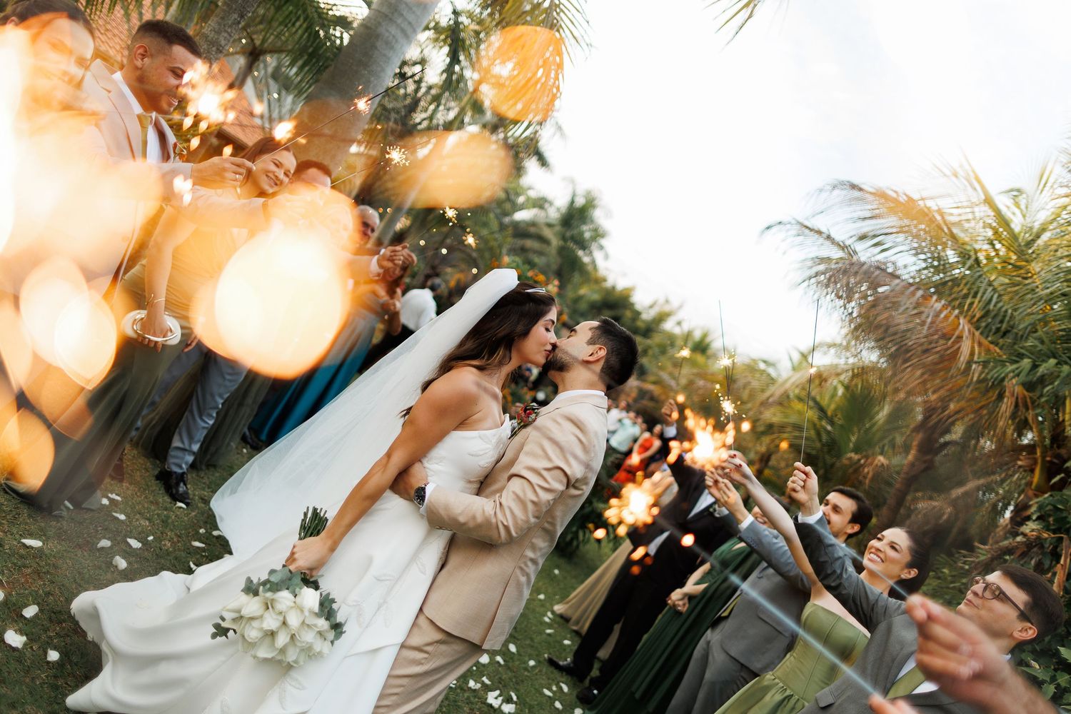 Wedding guests celebrate under warm string lights at an outdoor evening reception.