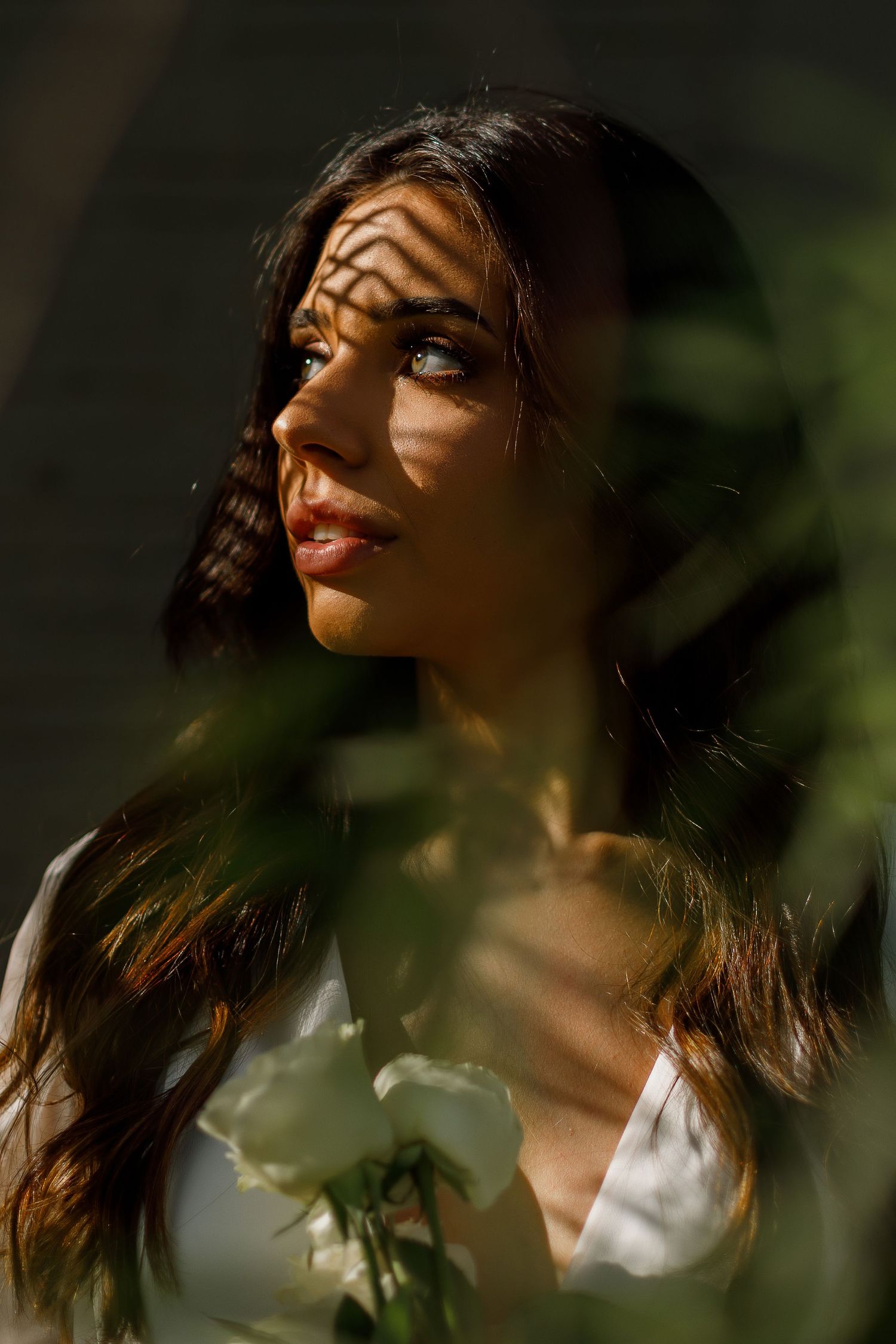 Artistic portrait with dramatic shadows and sunlight creating a moody atmosphere.