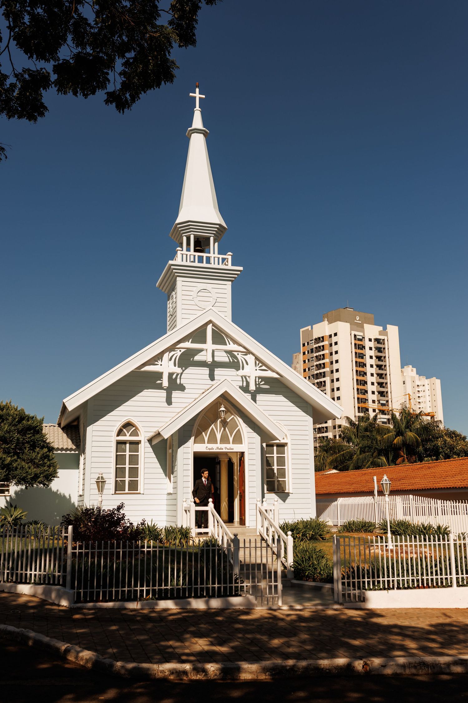 White wooden church with steeple and cross against deep blue sky.