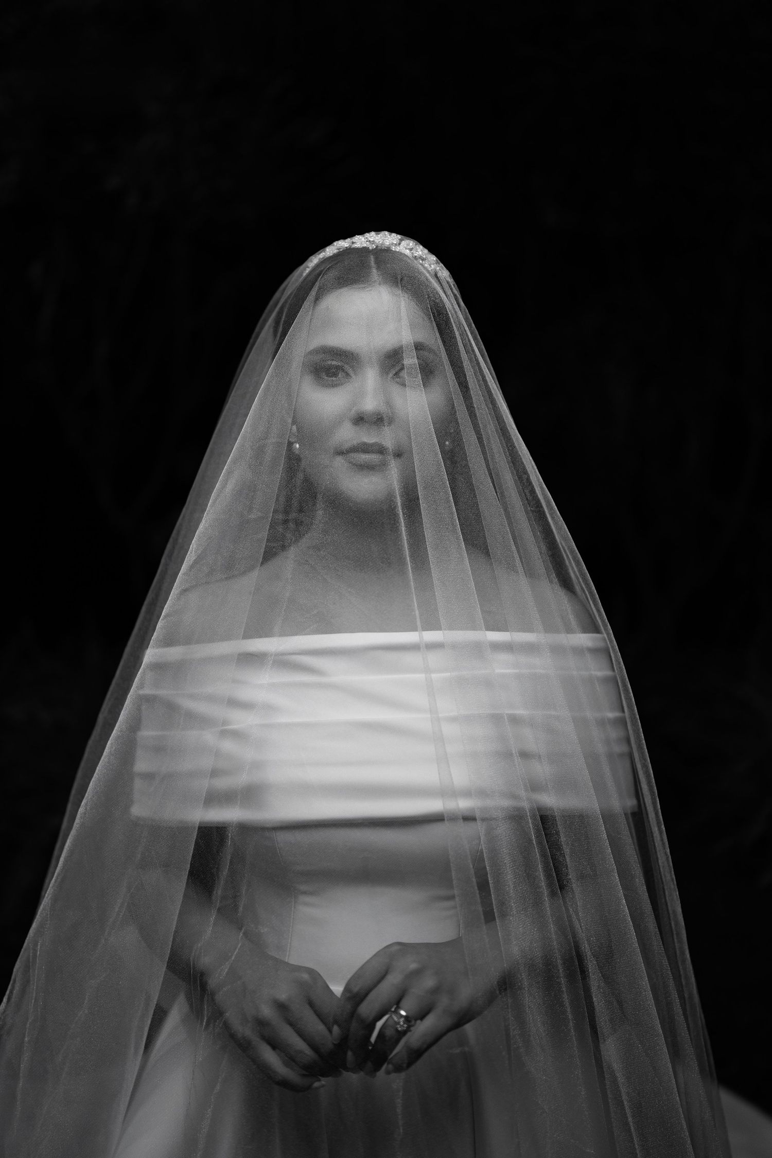 Artistic black and white portrait through a wedding veil with dramatic lighting.