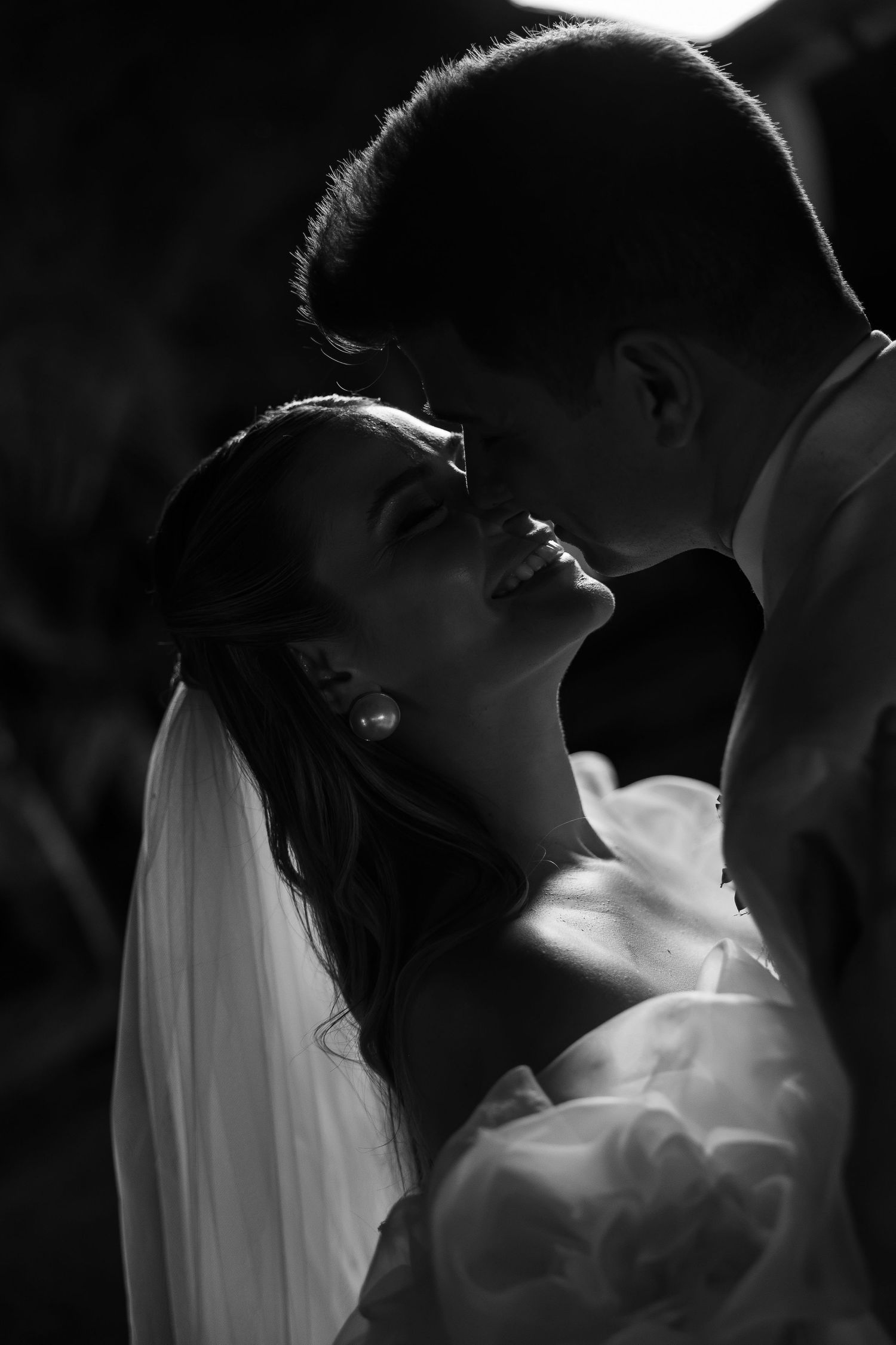Dramatic black and white silhouette of newlyweds sharing an intimate moment.