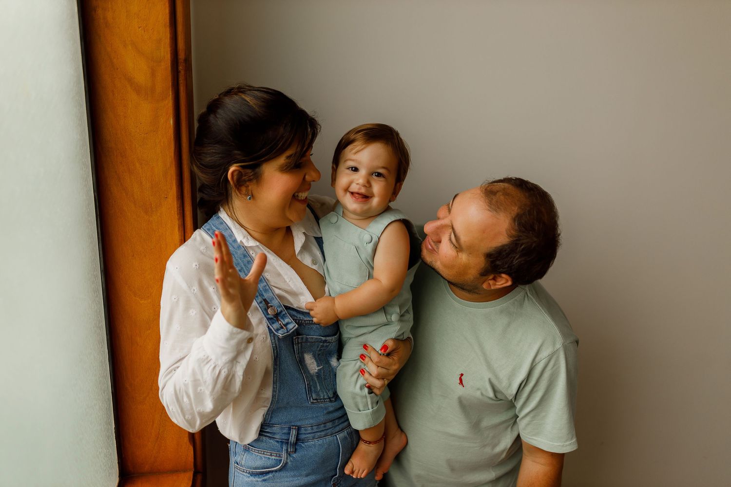 Family sharing joyful moments together against a light colored wall.