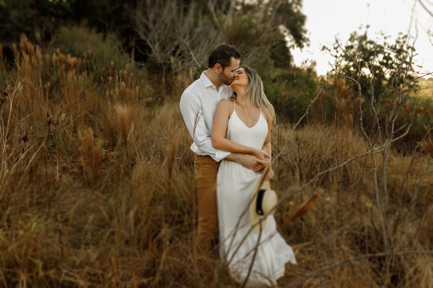 A tender moment captured between a couple in a rustic outdoor setting with warm lighting.