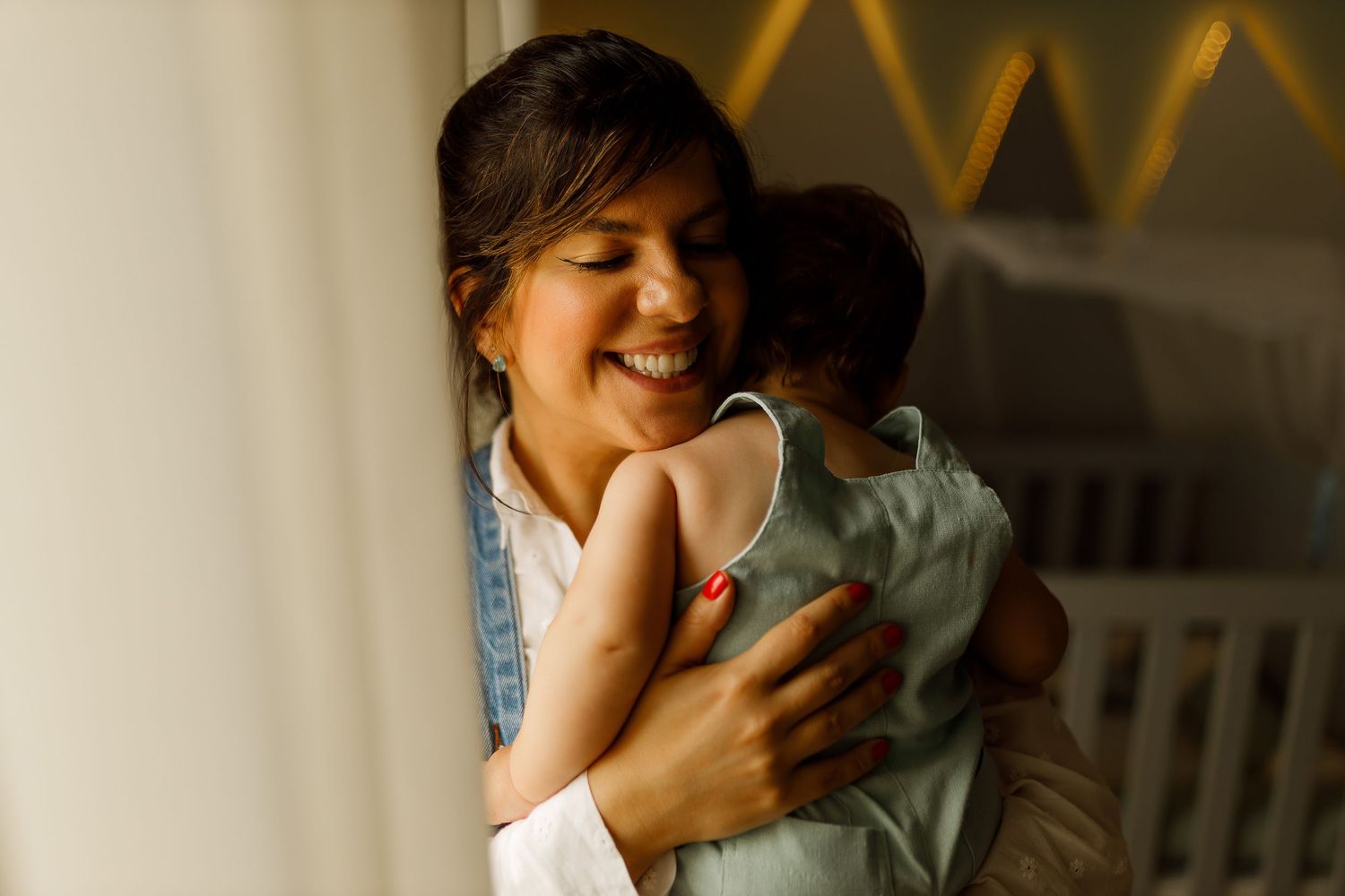 Intimate family moments captured in a nursery with natural window light.